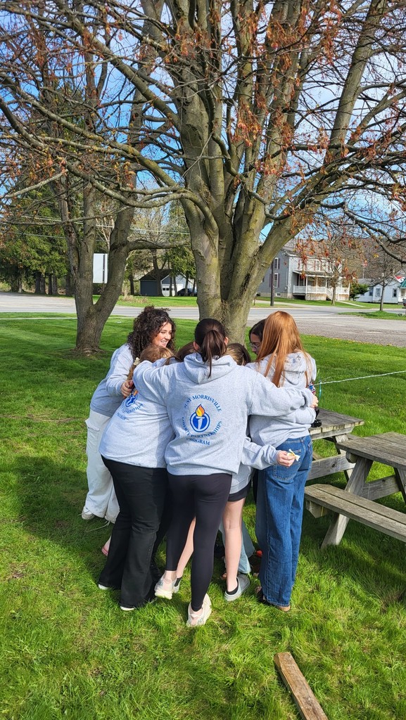 OV students and Liberty Partnerships Program mentors gathered in a circle outdoors for a group hug under a tree.