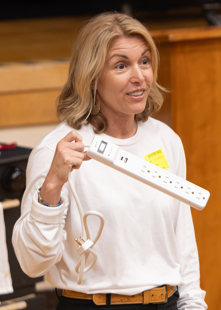 Guest presenter holds a power strip while explaining electrical safety during the presentation.