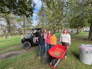 Group of students stand near a utility vehicle and wheelbarrow used during the clean-up.