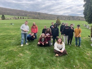Group of Otselic Valley students pose together in a cemetery during a community clean-up day.
