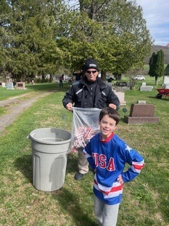 Student and adult volunteer hold a bag of collected debris during the clean-up effort.