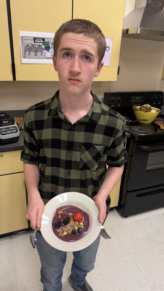 Students in a classroom preparing açaí bowls with fresh fruit and toppings during a cooking lesson.