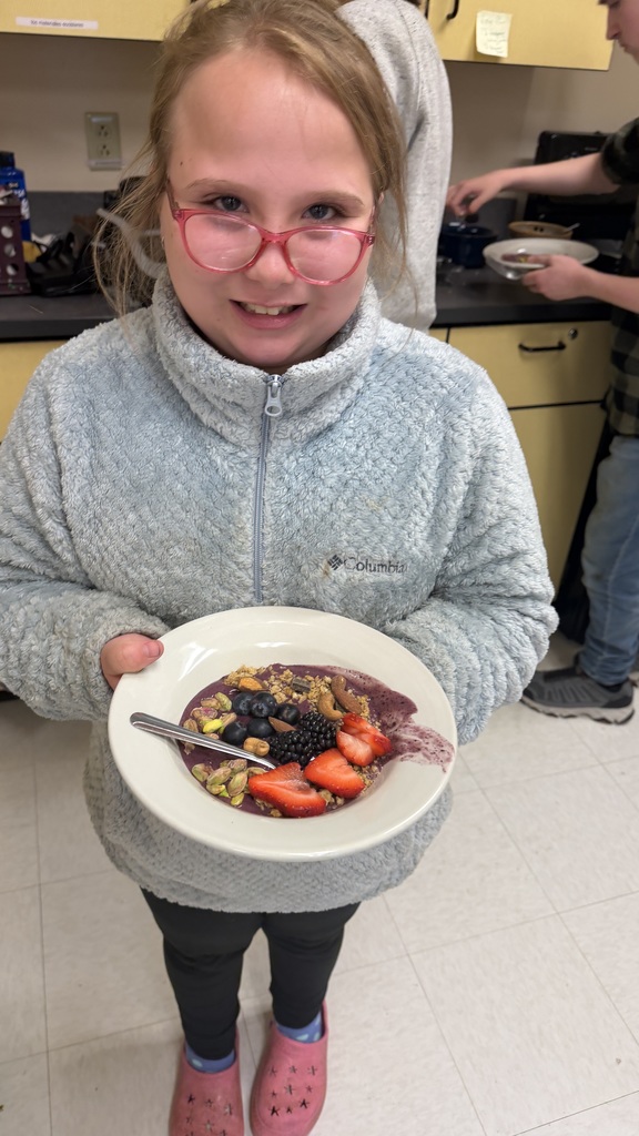 Students in a classroom preparing açaí bowls with fresh fruit and toppings during a cooking lesson.