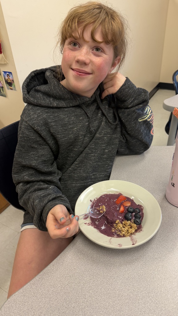 Students in a classroom preparing açaí bowls with fresh fruit and toppings during a cooking lesson.