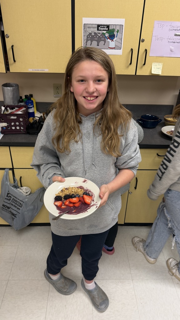 Students in a classroom preparing açaí bowls with fresh fruit and toppings during a cooking lesson.