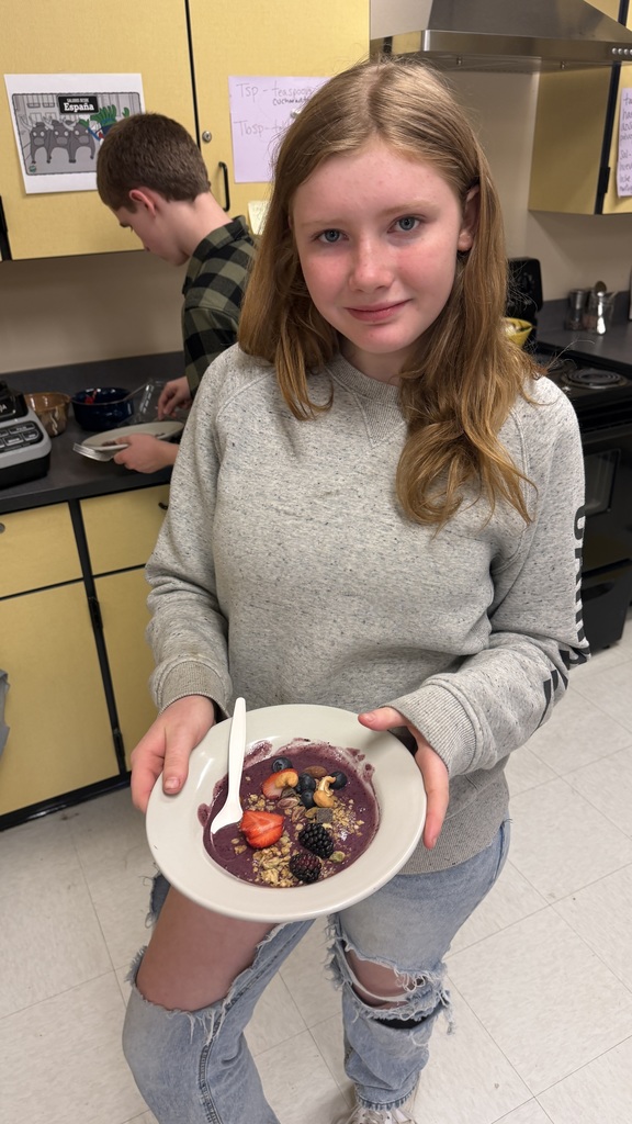 Students in a classroom preparing açaí bowls with fresh fruit and toppings during a cooking lesson.
