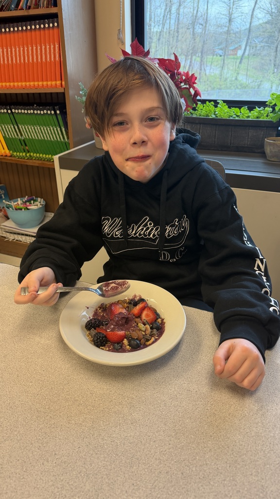 Students in a classroom preparing açaí bowls with fresh fruit and toppings during a cooking lesson.