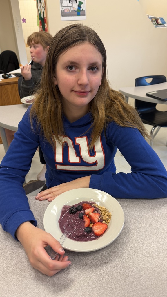 Students in a classroom preparing açaí bowls with fresh fruit and toppings during a cooking lesson.
