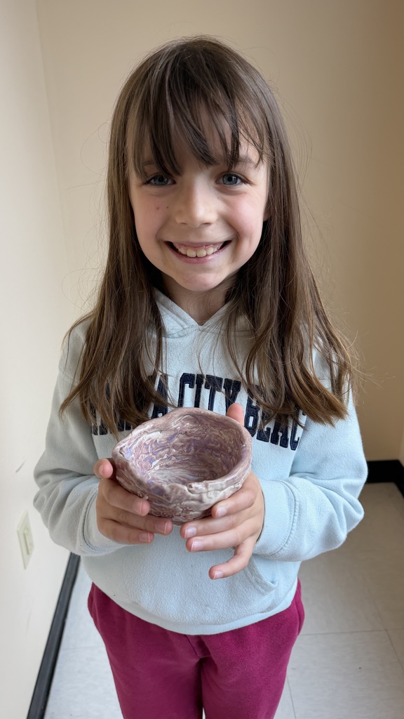 Finished glazed clay coil pots created by fourth grade students, displayed after completion of the classroom art project.
