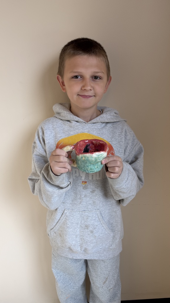 Finished glazed clay coil pots created by fourth grade students, displayed after completion of the classroom art project.