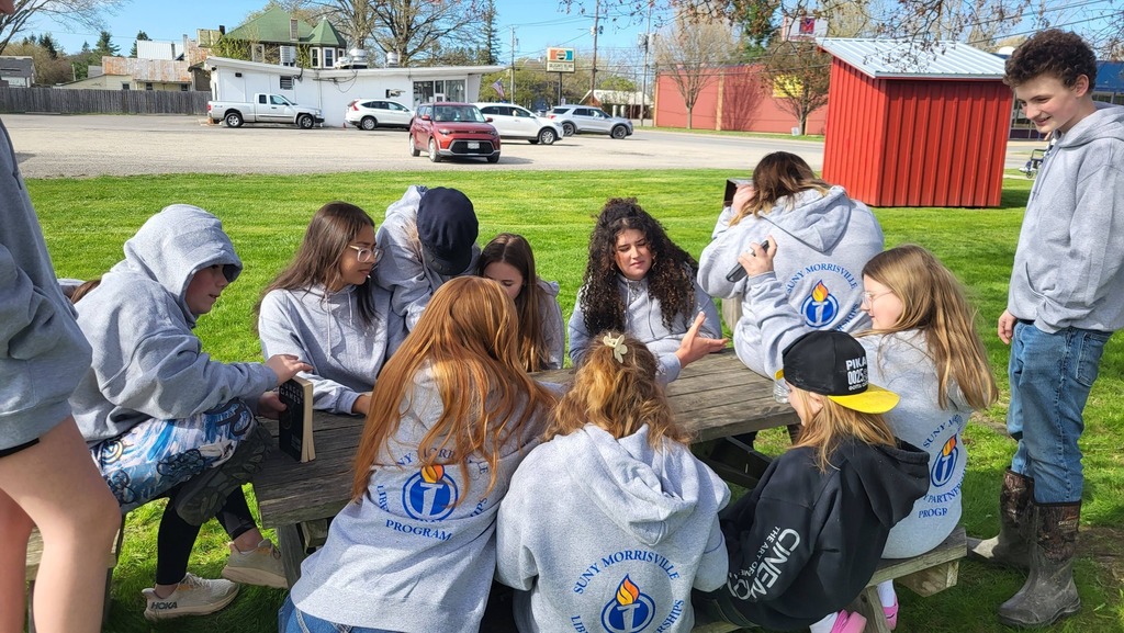 OV students and Colgate mentors gather outdoors for an end-of-year celebration, spending time together and smiling.