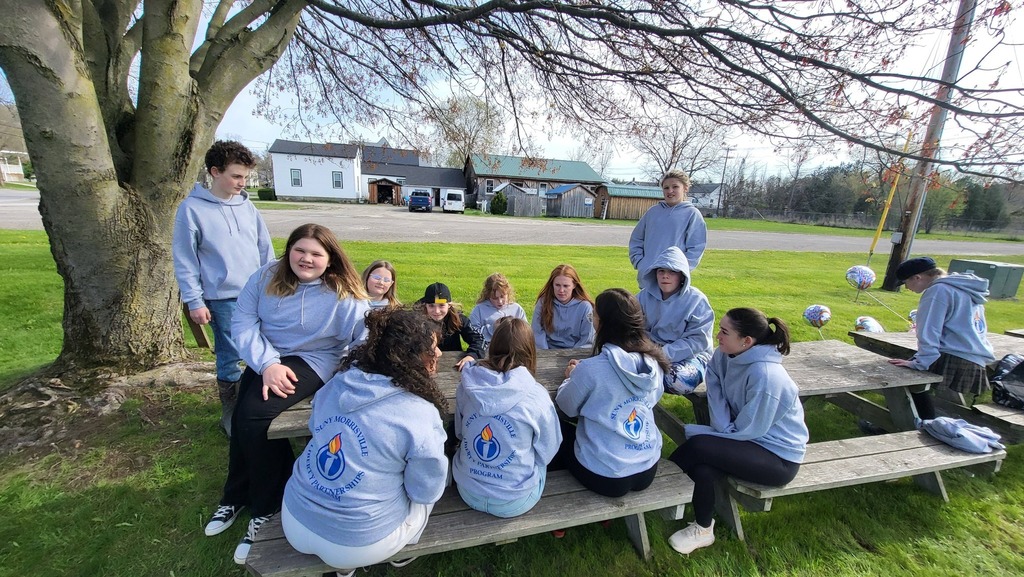 OV students and Colgate mentors gather outdoors for an end-of-year celebration, spending time together and smiling.