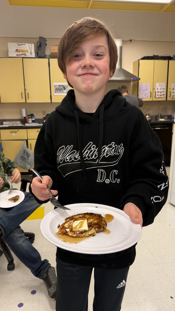 Sixth grade students prepare pancakes in a classroom cooking activity with help from classmates