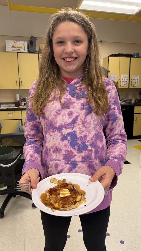 Sixth grade students prepare pancakes in a classroom cooking activity with help from classmates