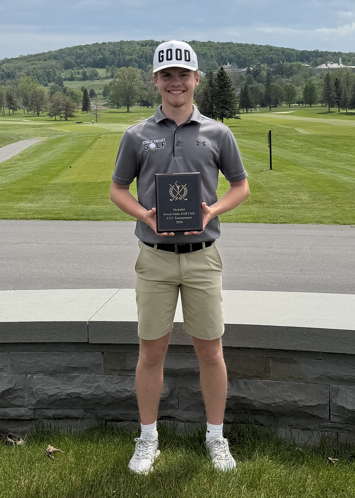 Student athlete Owen Davis stands outdoors holding his first-place CCL plaque after winning the CCL playoff at Seven Oaks. He is wearing golf attire and smiling, with a golf course and hills in the background.