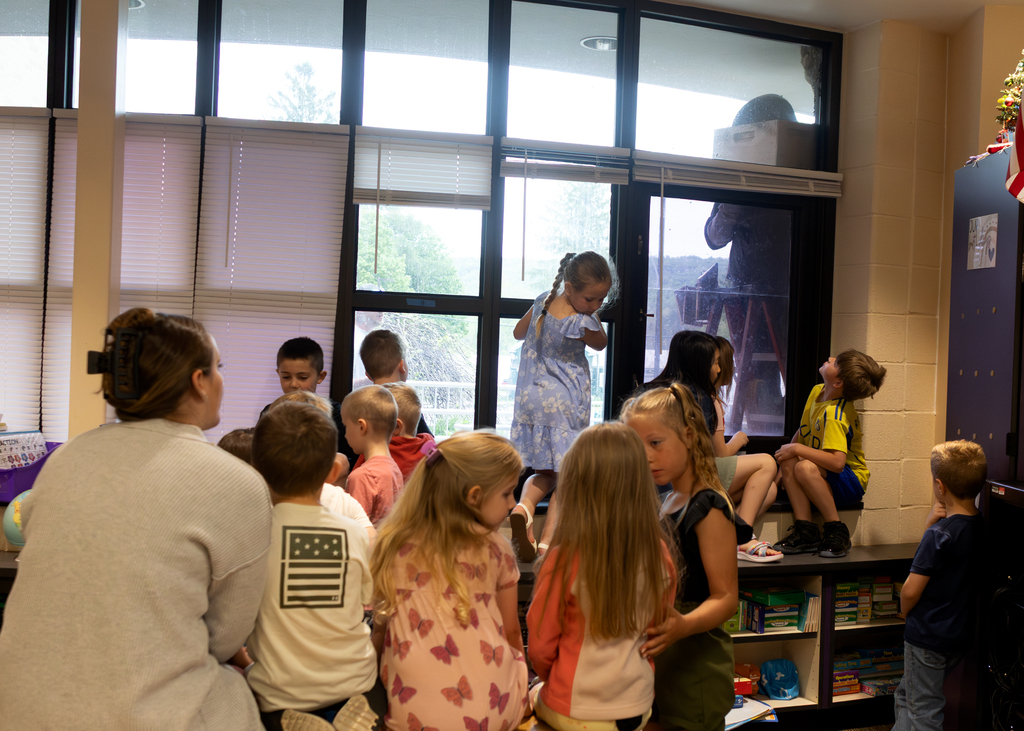 Photos of a beekeeper relocating a swarm of honey bees outside Otselic Valley while students observed from nearby classrooms.