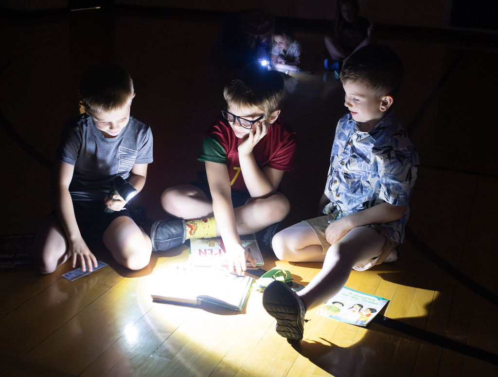 Kindergarten through second grade students participate in Flashlight Reading as part of the ABC Countdown to Summer, using flashlights while reading together with classmates.