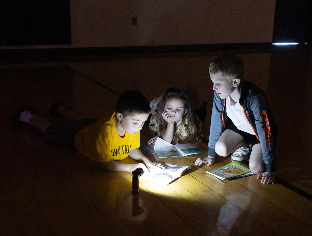 Kindergarten through second grade students participate in Flashlight Reading as part of the ABC Countdown to Summer, using flashlights while reading together with classmates.