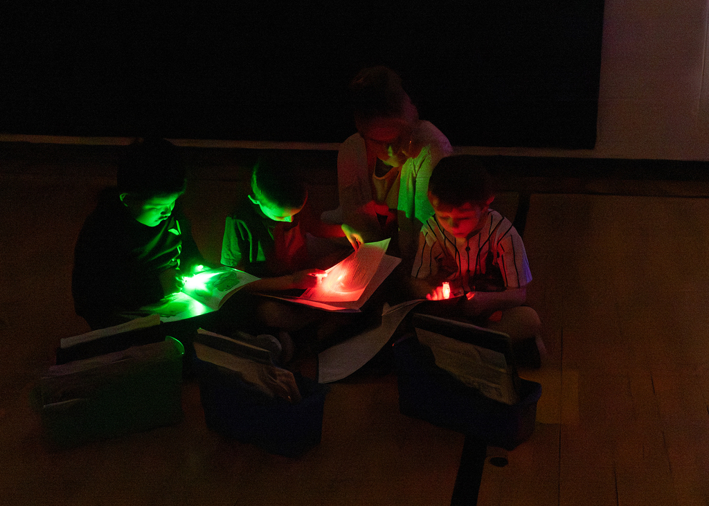 Kindergarten through second grade students participate in Flashlight Reading as part of the ABC Countdown to Summer, using flashlights while reading together with classmates.