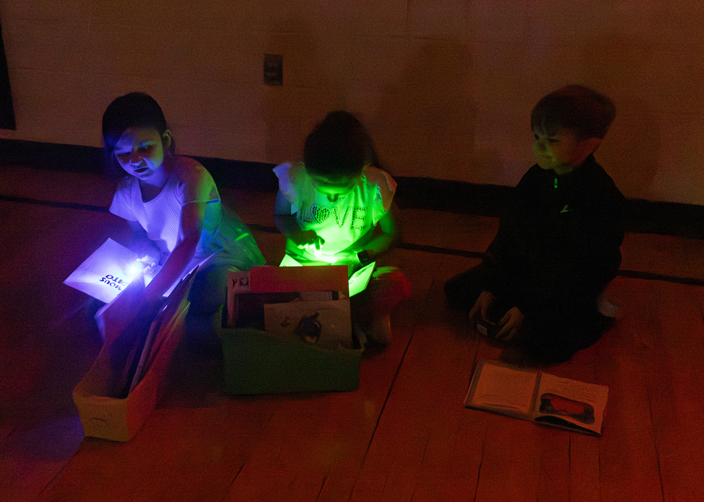 Kindergarten through second grade students participate in Flashlight Reading as part of the ABC Countdown to Summer, using flashlights while reading together with classmates.