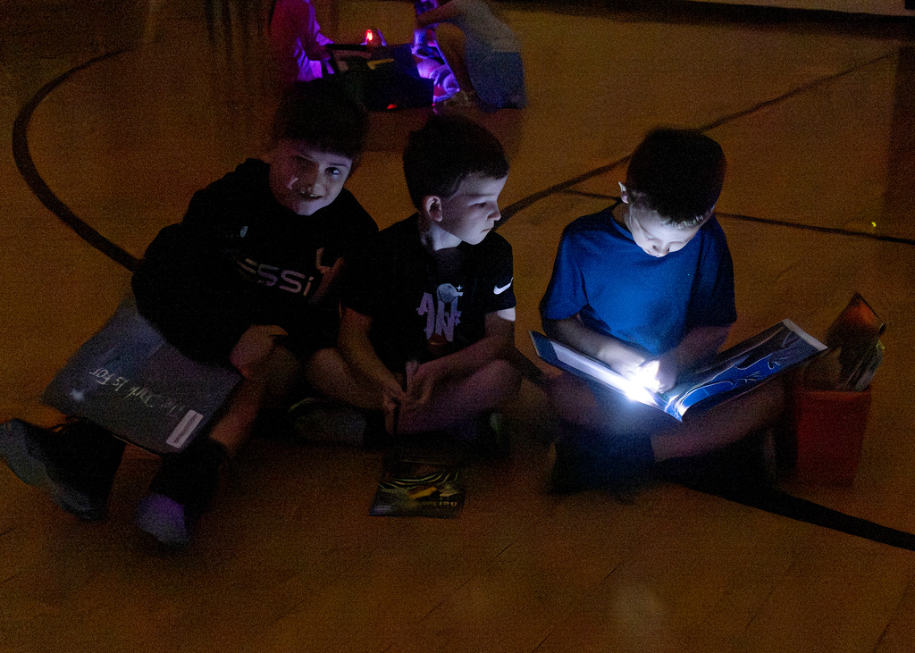 Kindergarten through second grade students participate in Flashlight Reading as part of the ABC Countdown to Summer, using flashlights while reading together with classmates.