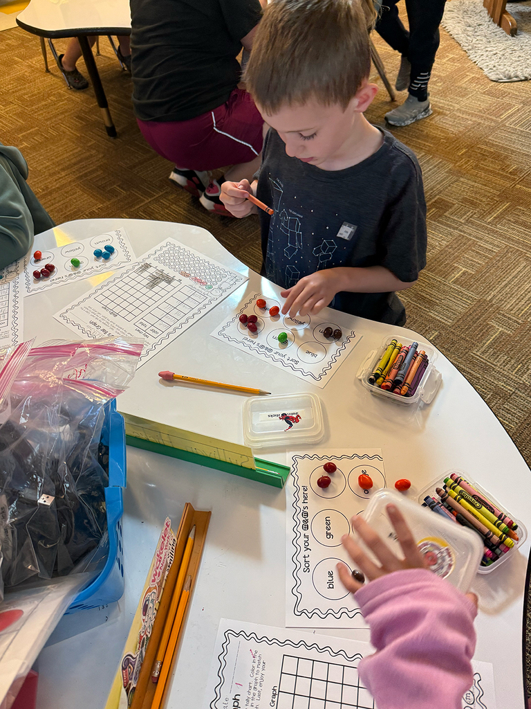 First grade students participate in a hands-on math activity using M&Ms to practice sorting, tally charts, and graphing skills in the classroom.