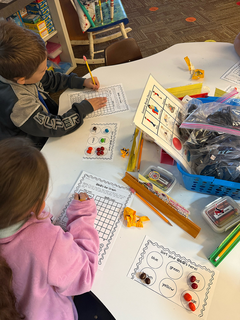First grade students participate in a hands-on math activity using M&Ms to practice sorting, tally charts, and graphing skills in the classroom.