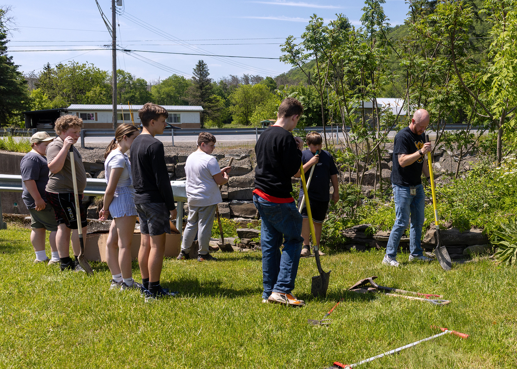 Middle school students plant young willow trees along the bank of Ashbell Brook near Otselic Valley school property as part of an erosion prevention and environmental stewardship project.