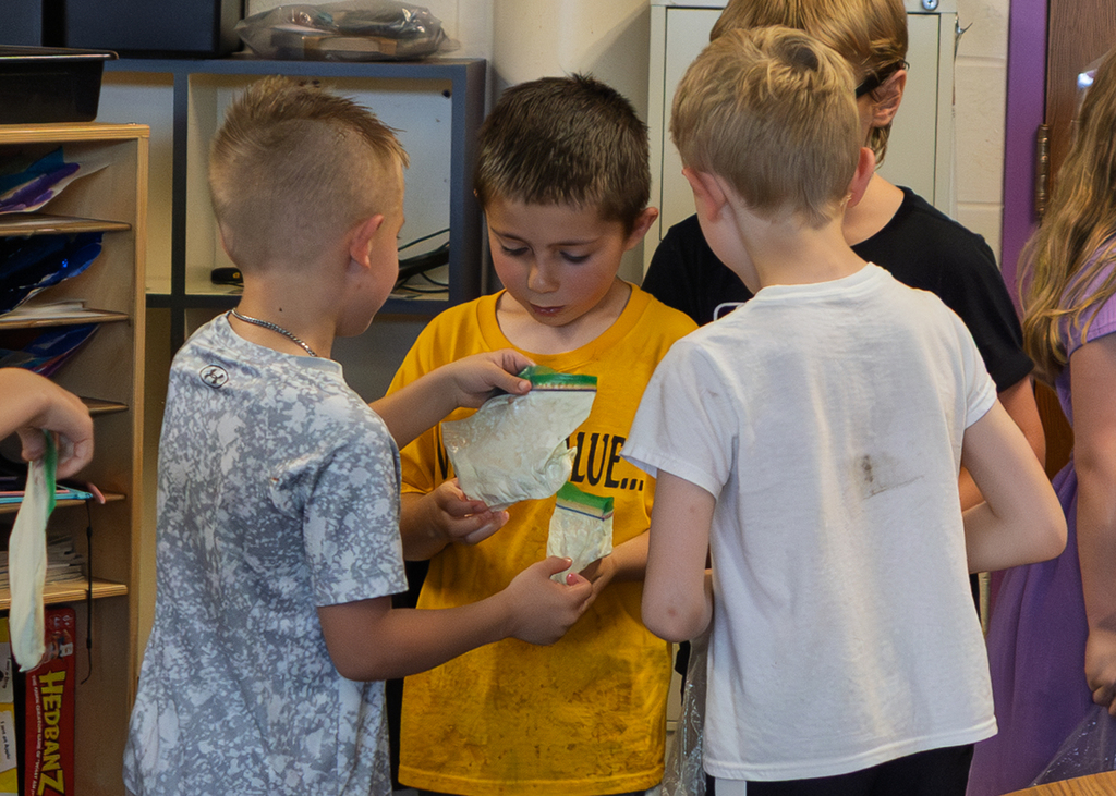 Mrs. Marston's second grade students work together to make homemade ice cream with Mr. Harvey. Students take turns helping with the process and enjoy tasting the finished treat.