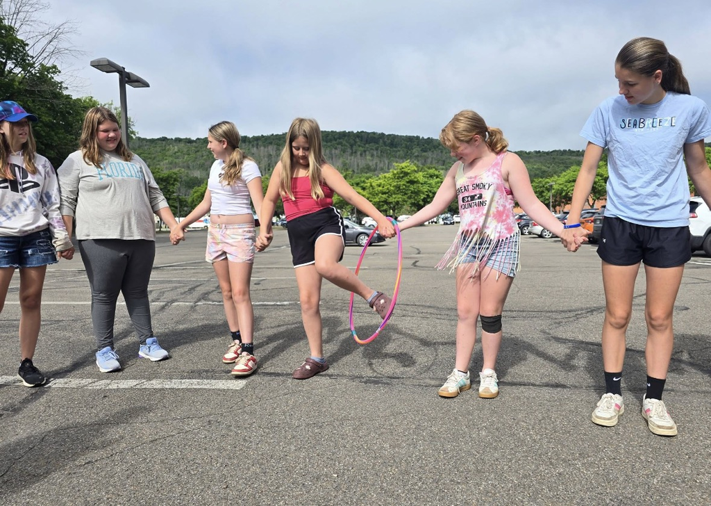 Students holding hands and passing their bodies through a hulahoop