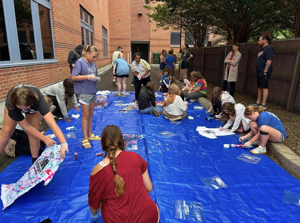 Students sitting on blue tarp doing crafts