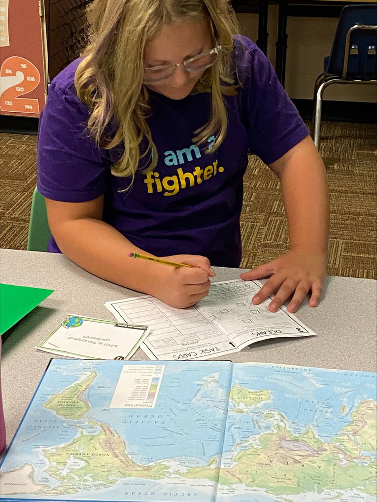 Student writing by a map
