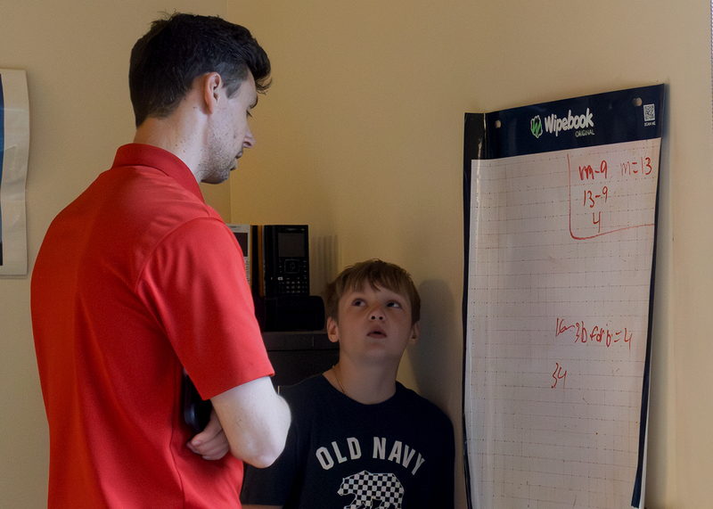 Teacher works with a student at a portable whiteboard during math class.