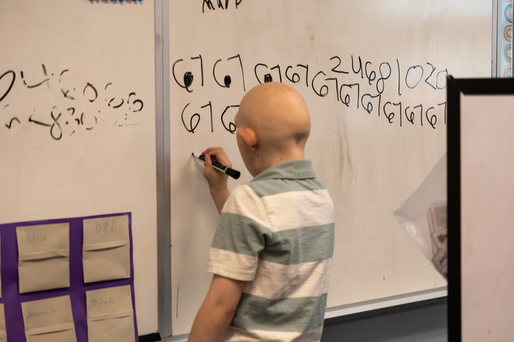 Kid writing on white board.