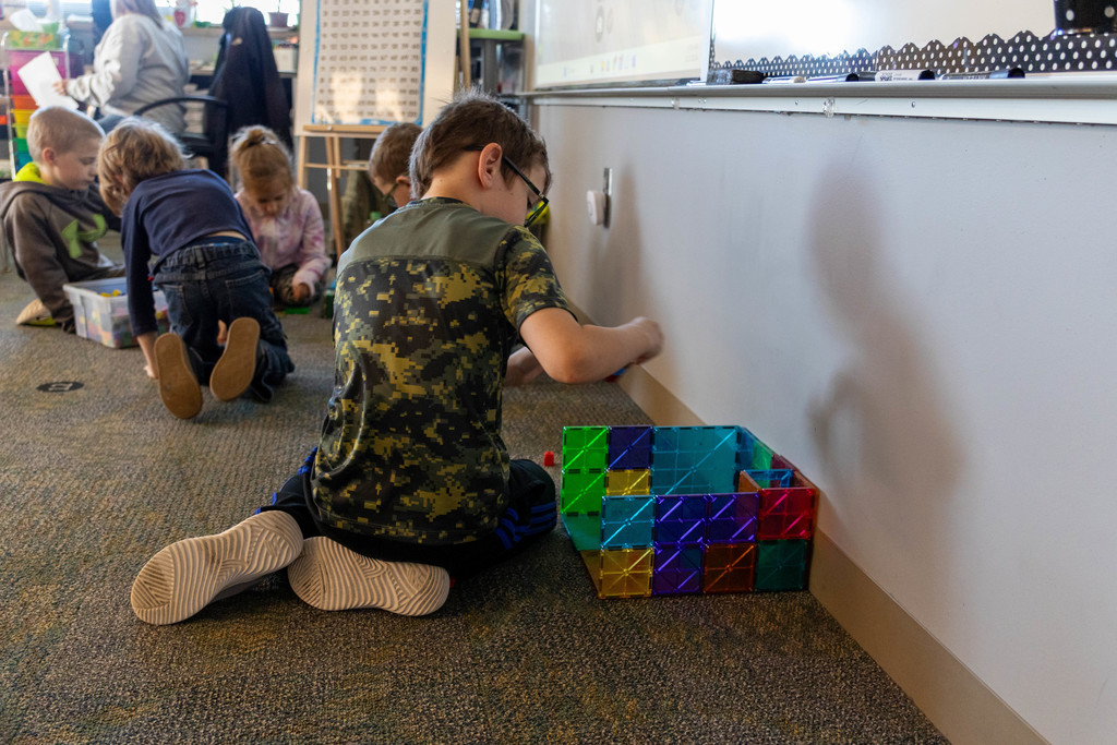 Kid building magnet tiles.