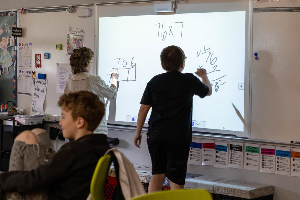 Kids doing math problems on the board.