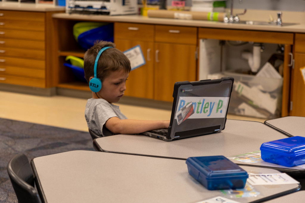 Kids listening to his Chromebook and working.