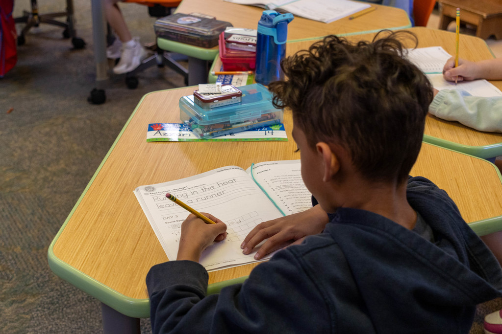 Kid writing in book.