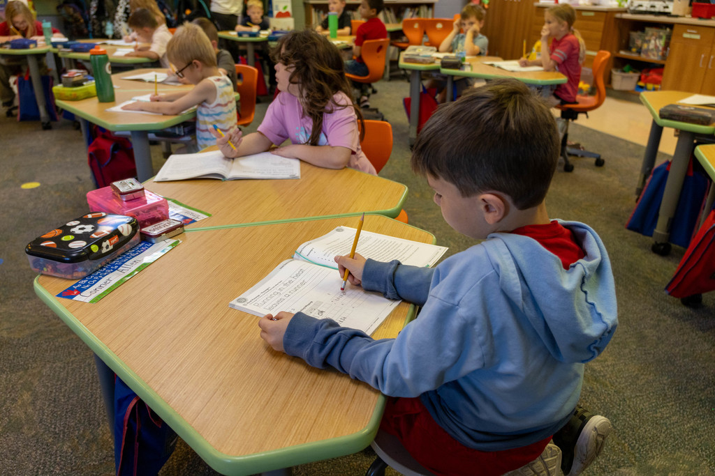 Kid writing on book.