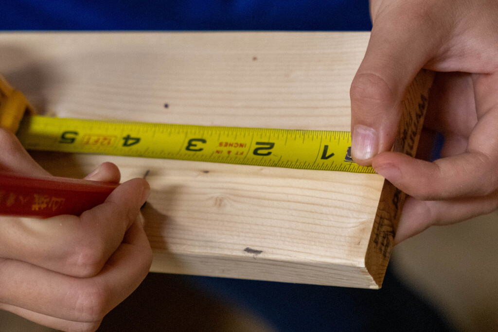 Student is marking where the wood will be cut using a tape measurer.
