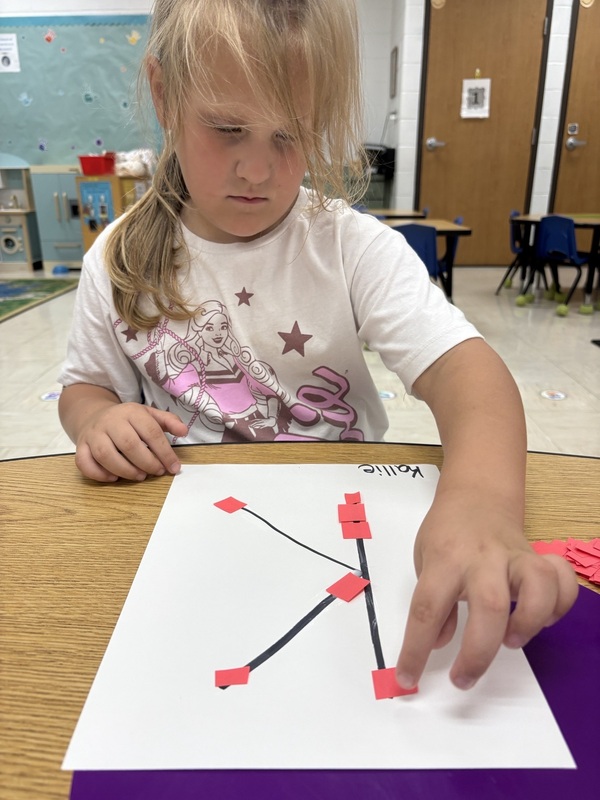 A pre-k student Working on fine motor skills with letters 