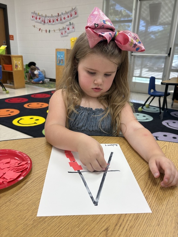 A pre-k student Working on fine motor skills with letters 