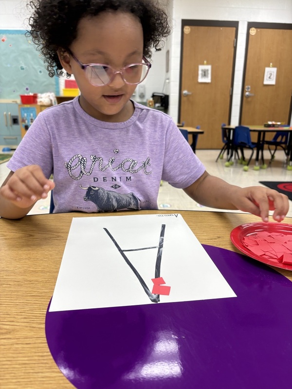 A pre-k student Working on fine motor skills with letters 
