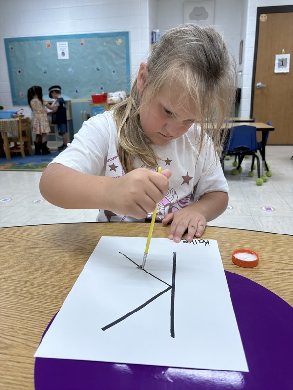 A pre-k student Working on fine motor skills with letters 