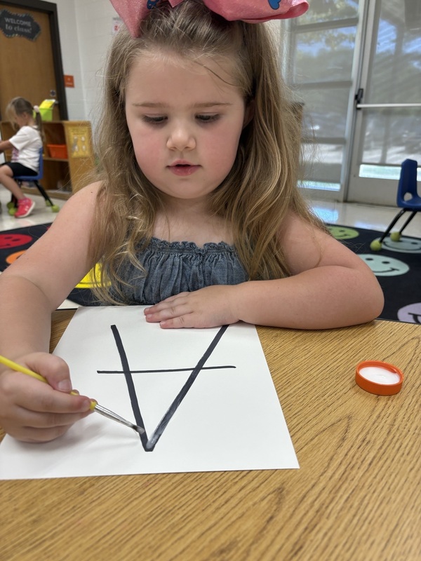 A pre-k student Working on fine motor skills with letters 