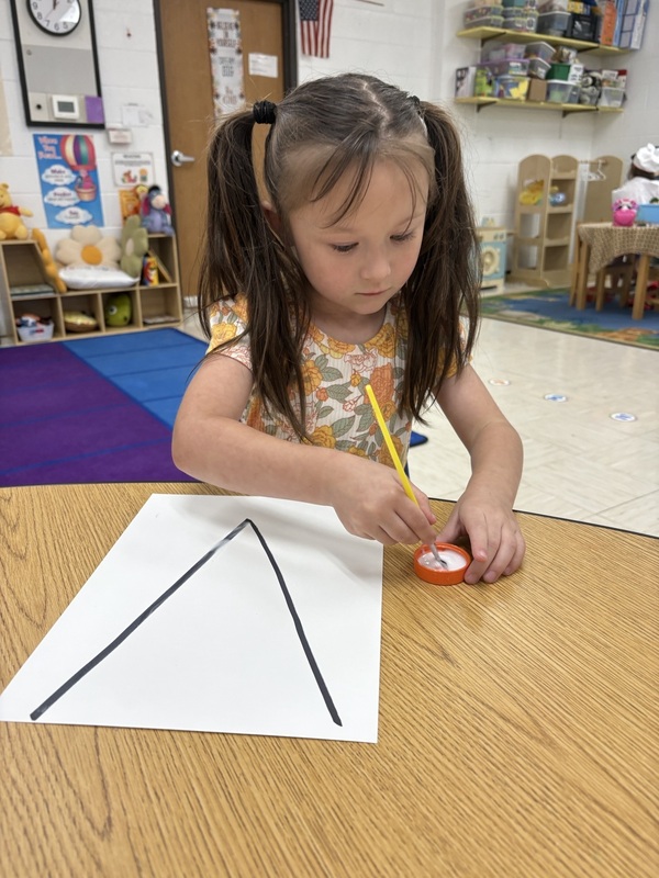 A pre-k student Working on fine motor skills with letters 
