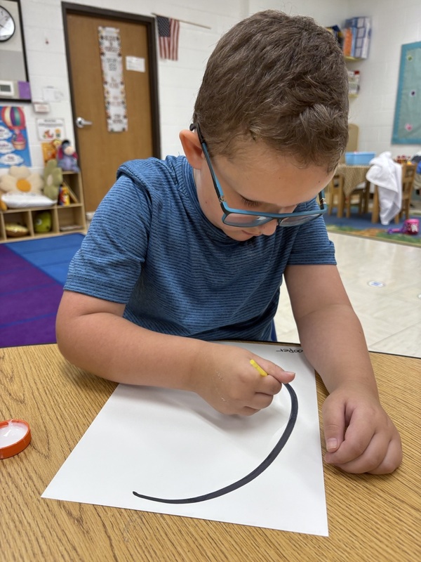 Pre-K student working on fine motor skills tracing letters