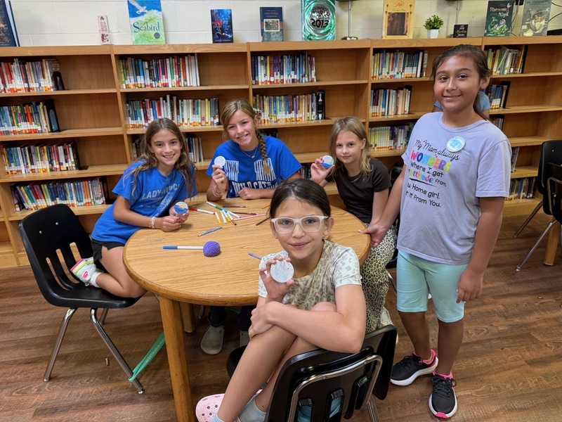 5th grade students making buttons in library