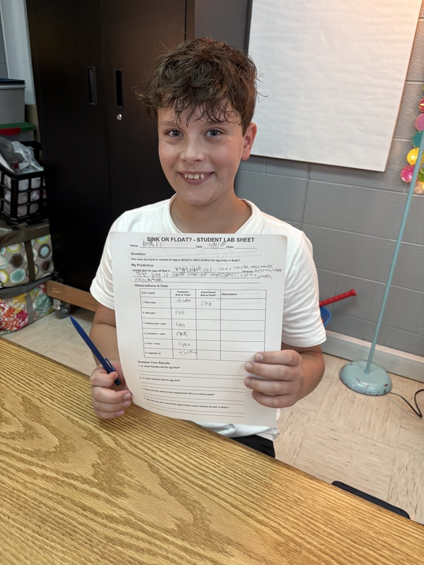 6th grade student posing with lab sheet