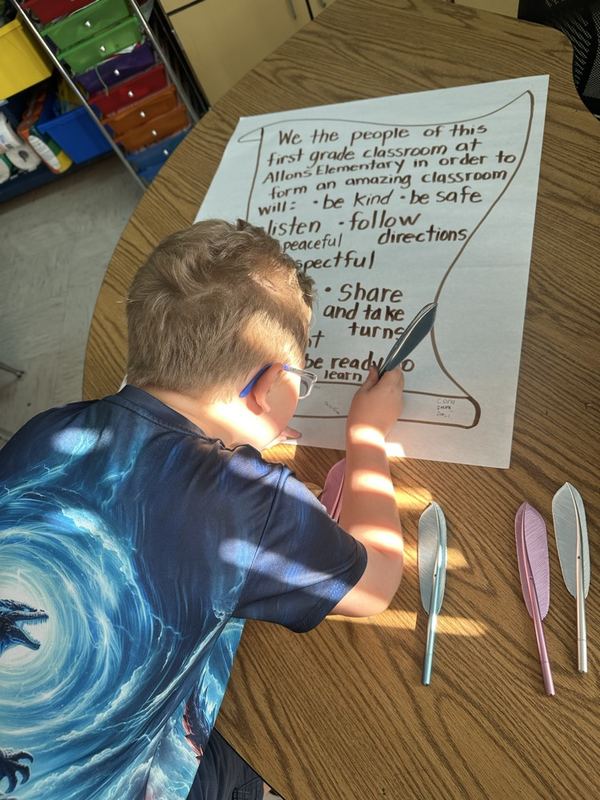 first grade students signing their classroom constitution with feather pens